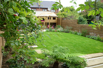 cleared and maintained green garden with wooden childrens house at end by Bizzy in the Garden